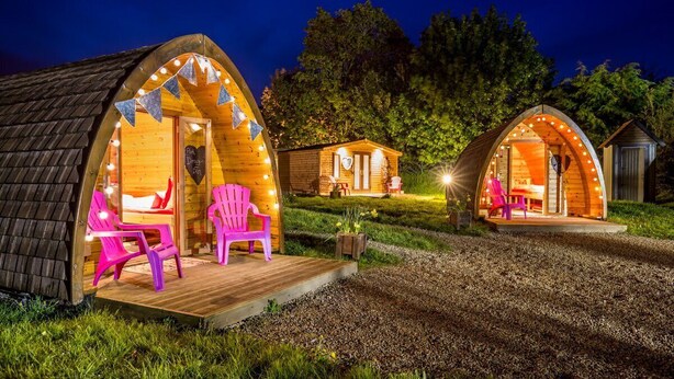 Three wooden cabins with arched roofs, each with a porch and outdoor seating. - Podumna Village  (Portumna)