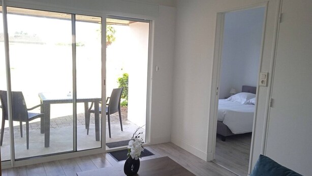 A modern hotel room with a large sliding glass door leading to an outdoor patio area. - Gîte "des Flots" Proche mer (Saint-Michel-en-l'Herm)