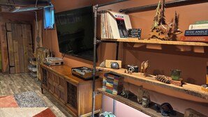 Ein Zimmer mit Holzschrank, Fernseher und Regalen mit Büchern und Dekoration.