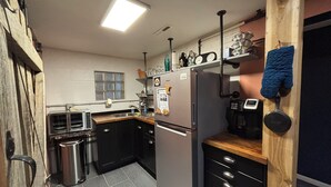 Eine kompakte Küche mit Kühlschrank, Herd, Spüle und einem Fenster mit Jalousien.