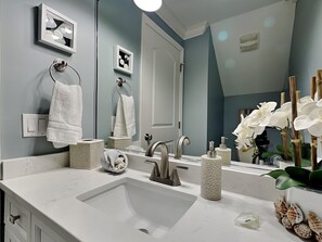 Ein modernes Badezimmer mit einem großen Spiegel, einem weißen Marmorwaschbecken und einem Waschtisch mit Handtuchhalter.