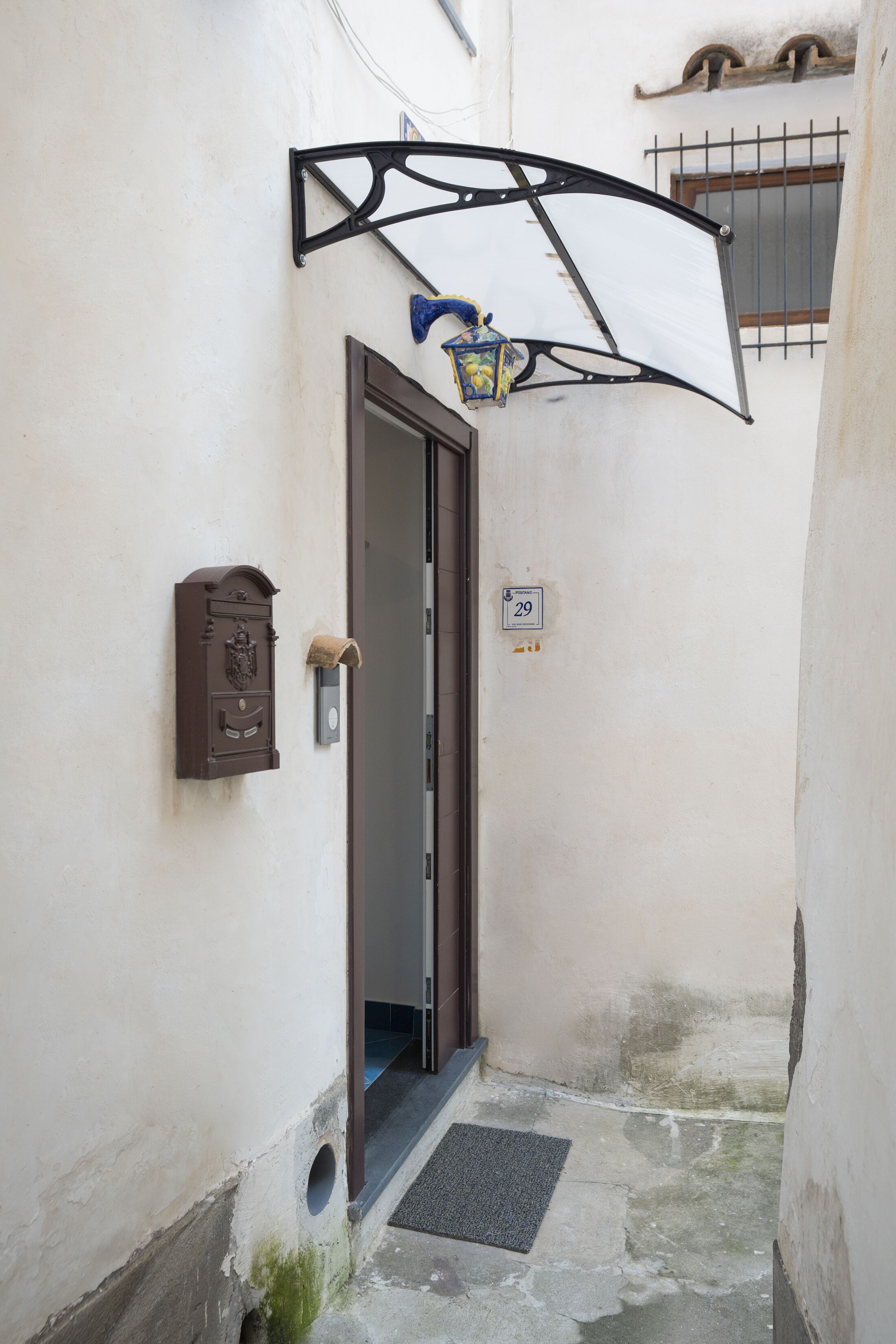 A narrow alleyway with a door, a mailbox, and a number plate.