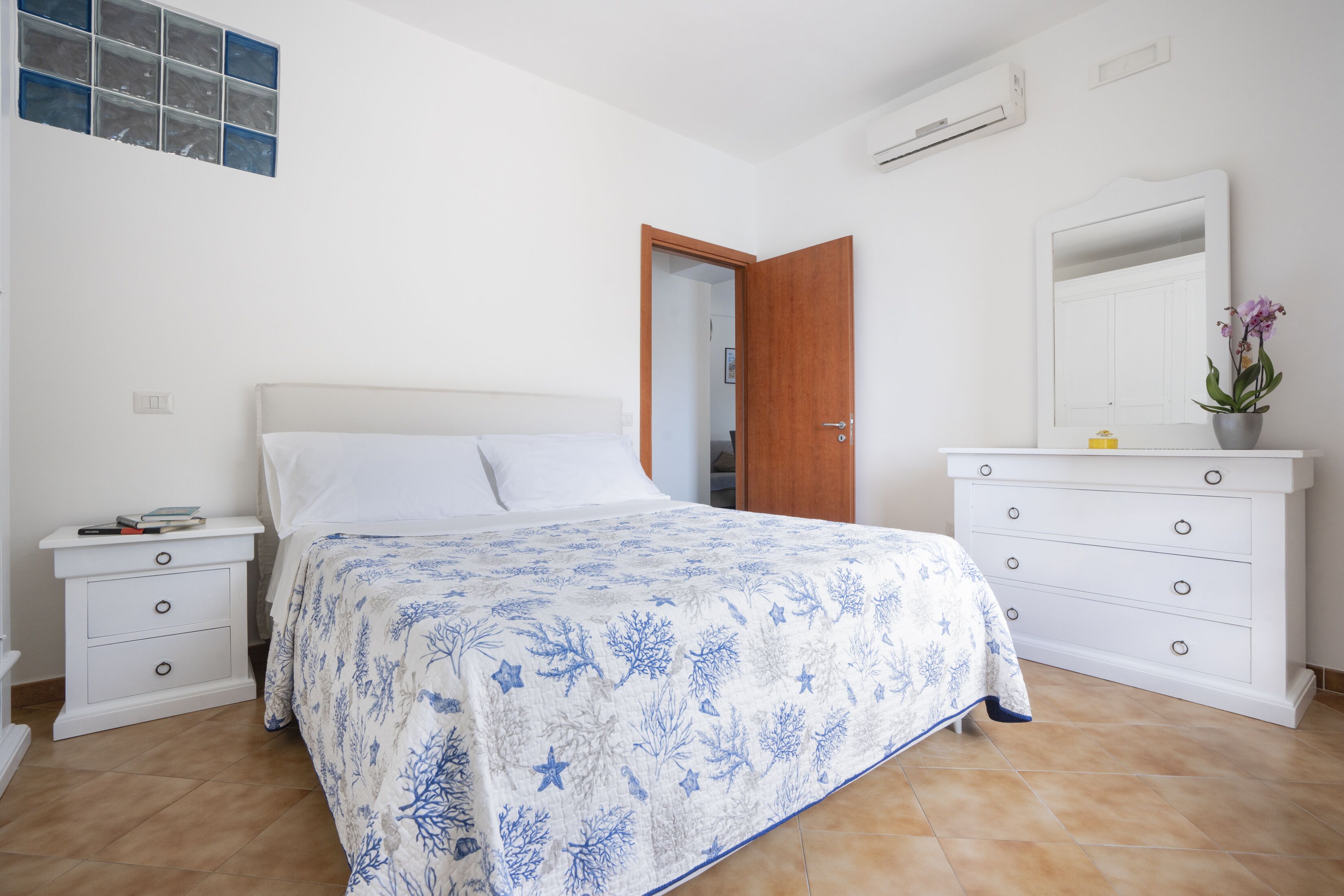 A bedroom with a bed, a nightstand, a dresser, and a mirror.