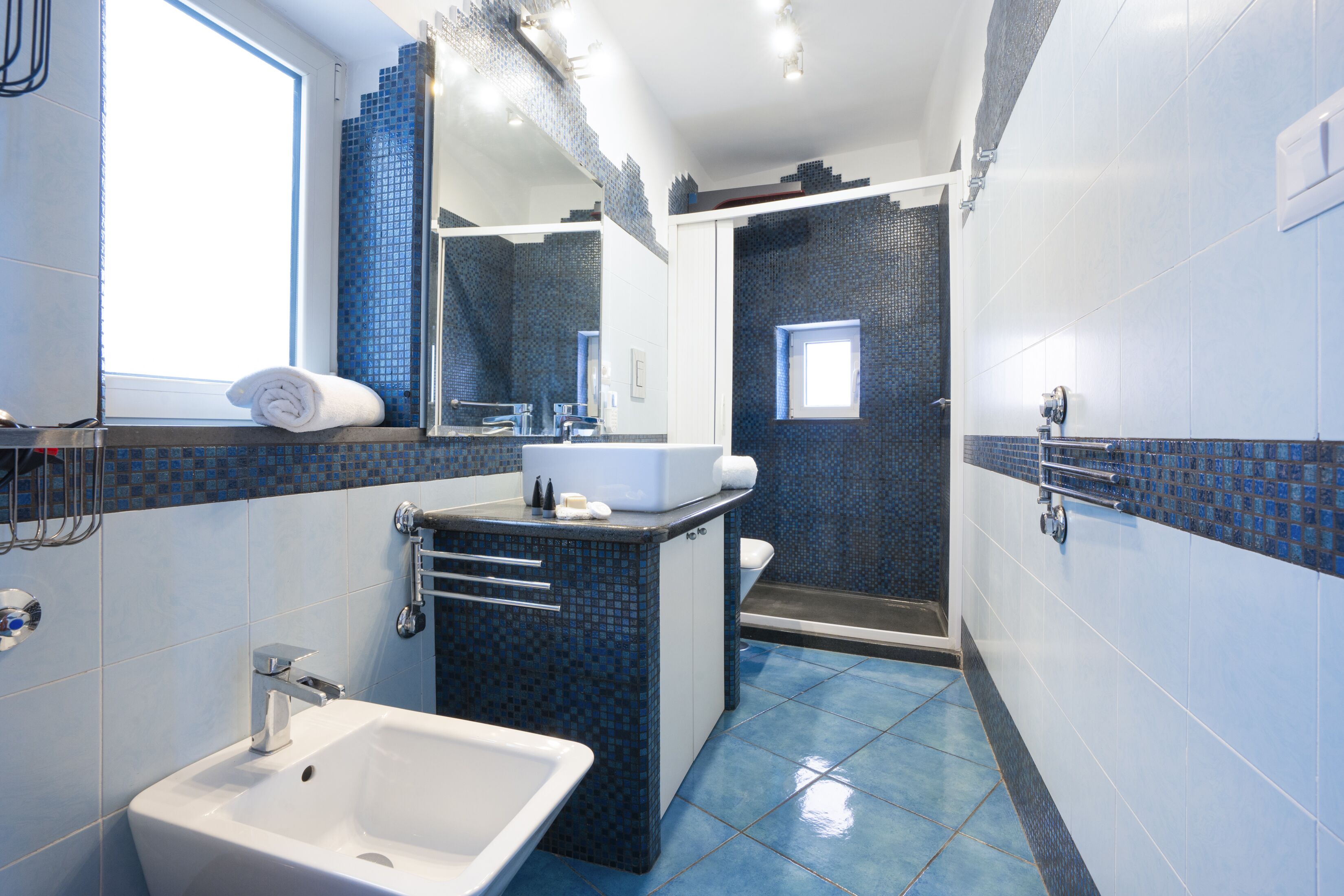 A modern bathroom with a large sink, a mirror, and a shower area.