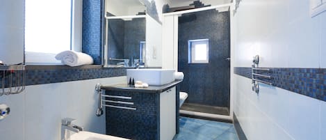 A modern bathroom with a large sink, a mirror, and a shower area.