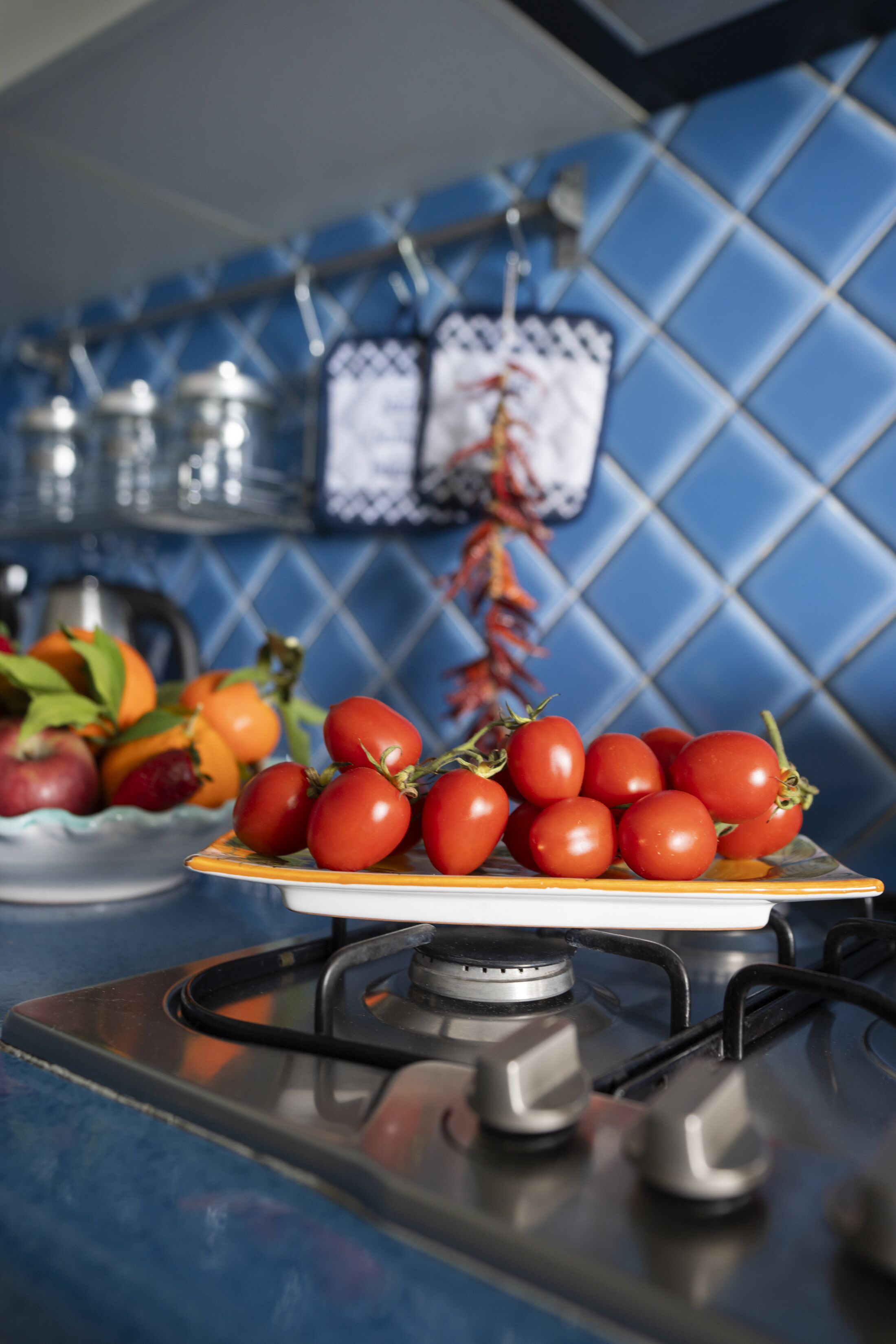 Une cuisine équipée d’une cuisinière à gaz, une assiette de tomates cerises et un saladier de fruits.