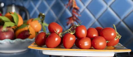 Une cuisine équipée d’une cuisinière à gaz, une assiette de tomates cerises et un saladier de fruits.
