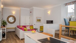 Een moderne woonkamer met een witte bank, een eettafel en een keukenhoek.