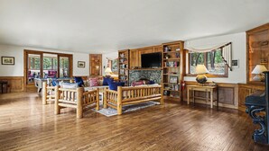 Un salón amplio con muebles de madera, chimenea y televisor.