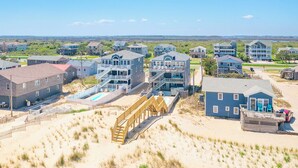 Eine Wohngegend an der Küste mit Häusern, einer Holzbrücke und einem Sandstrand.