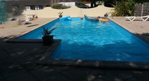 A rectangular swimming pool with a tiled deck, surrounded by a sandy area and some potted plants. - Villa "du Lagon" Avec Piscine (Saint-Michel-en-l'Herm)