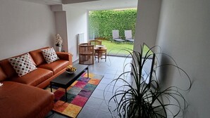 A living room with a brown leather sofa, a colorful rug, and a large potted plant. - Ferienwohnung auf der Höri, Terrasse und Garten, 8 Minuten Fußweg zum Bodensee (Gaienhofen)