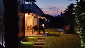 A backyard with a wooden deck, a covered patio, and outdoor seating. - Ferienwohnung auf der Höri, Terrasse und Garten, 8 Minuten Fußweg zum Bodensee (Gaienhofen)