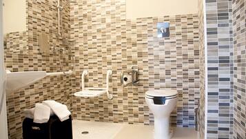 A bathroom with a mosaic tile wall, a toilet, a sink, and a shower area.