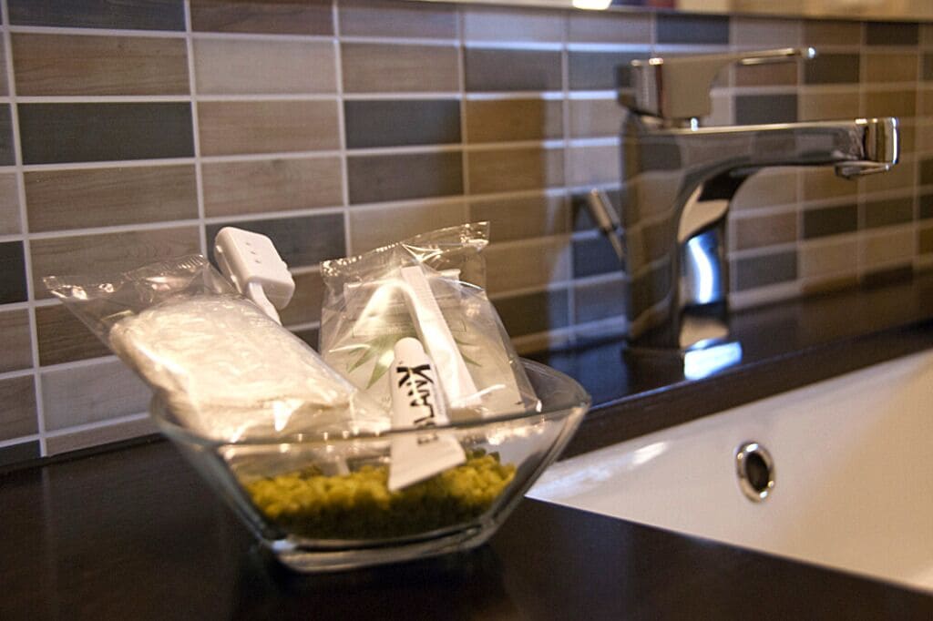 Un saladier en verre contenant des aliments emballés, posé sur un plan de travail de cuisine, avec un robinet moderne.