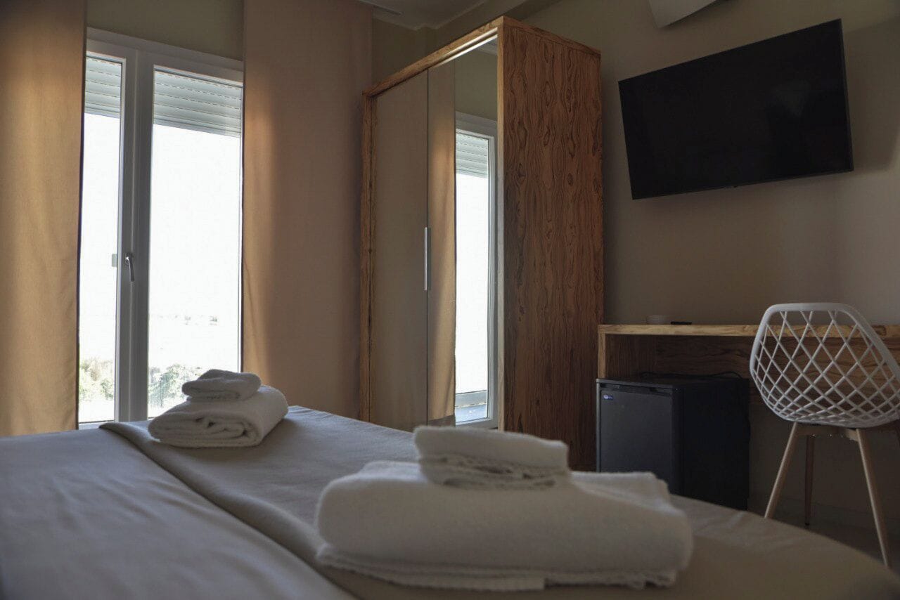 Une chambre d’hôtel avec un lit, un bureau, une chaise et un téléviseur fixé au mur.