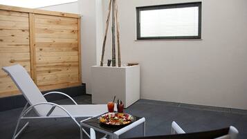 Un patio con una mesa blanca, dos sillas blancas, una cerca de madera y una ventana con persianas.