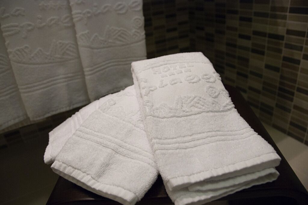 A stack of white towels with embossed text on a dark surface in a bathroom with patterned tiles.