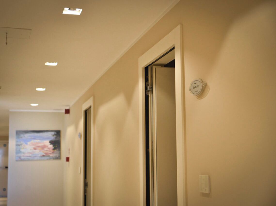 A hallway with doors, a wall-mounted sign, and a painting.