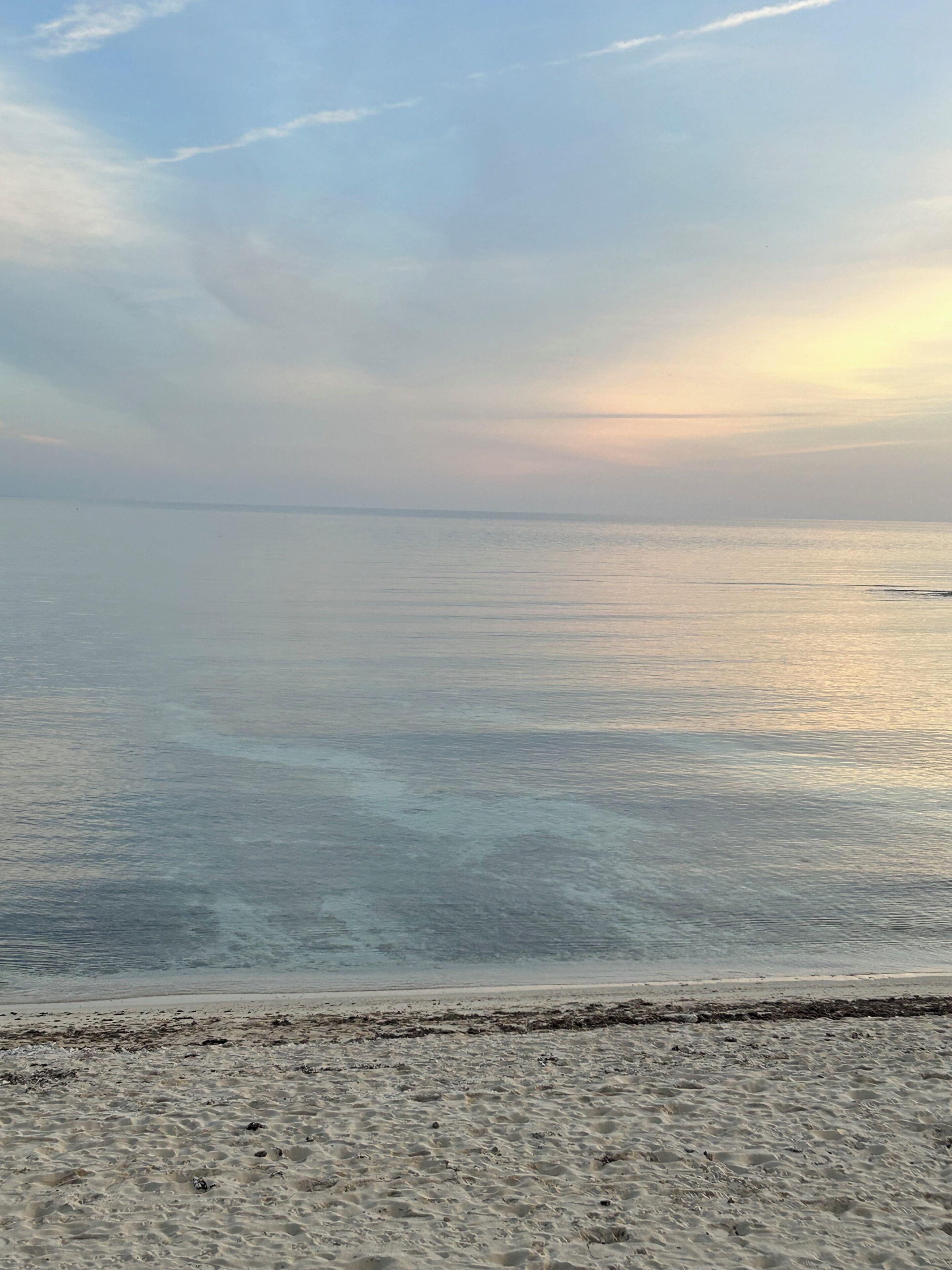 Una spiaggia con acque limpide e una riva sabbiosa.