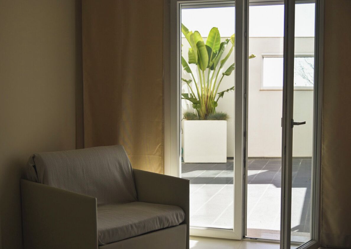 A room with a sofa, a sliding glass door leading to an outdoor area with a potted plant.