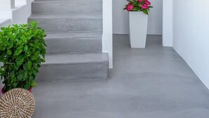 A modern staircase with a wooden railing, a potted plant, and a flower arrangement. - Esperanza Apartment (Adamantas)