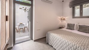 A bedroom with a bed, a window, and a door leading to a balcony. - Esperanza Apartment (Adamantas)