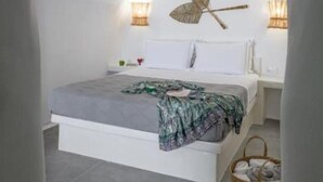 A bedroom with a bed, bedside lamps, a wall-mounted decorative piece, and a woven basket. - Esperanza Boathouse (Mandrakia)