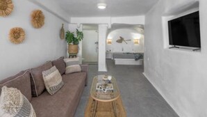 A modern living room with a sofa, coffee table, and a TV mounted on the wall. - Esperanza Boathouse (Mandrakia)