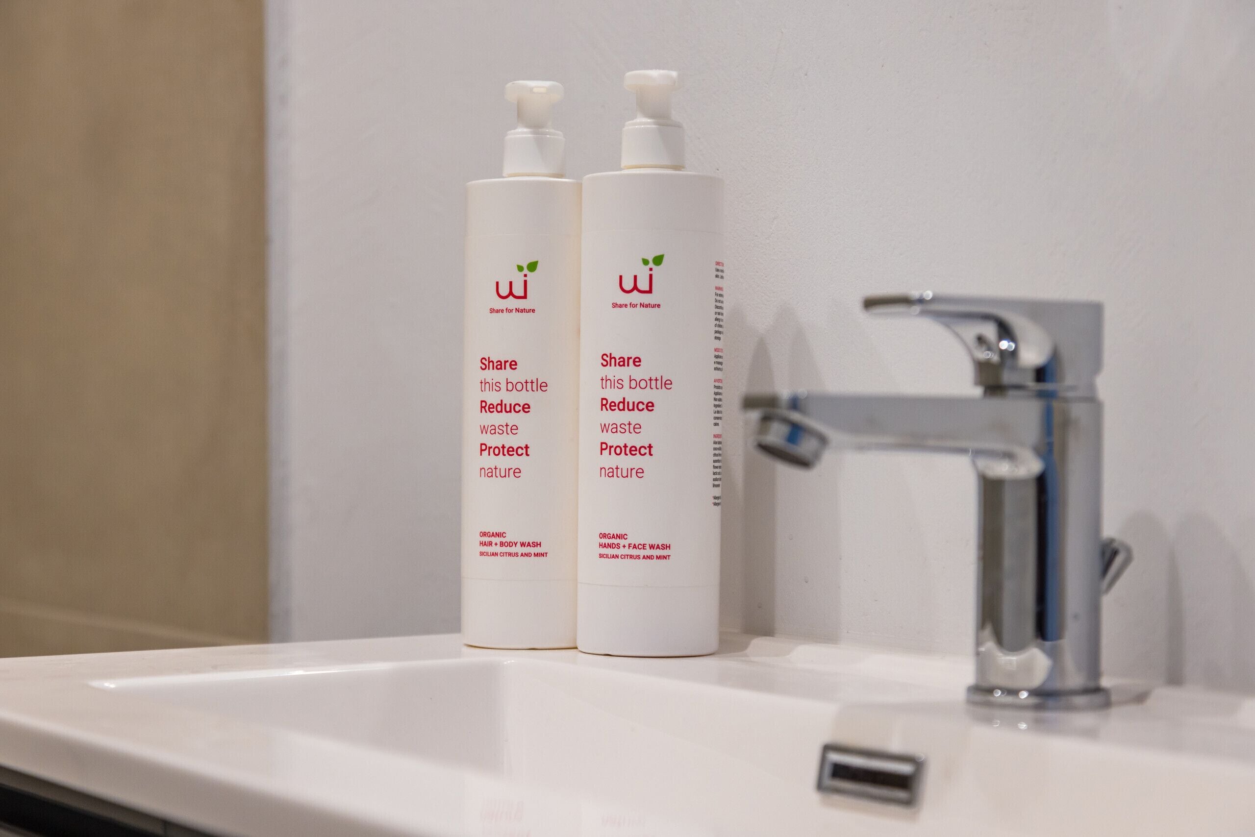 Two bottles of organic hand and body wash on a bathroom sink.