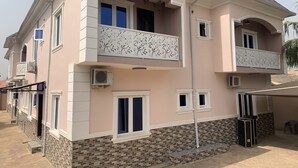A two-story building with a balcony on the second floor, a tiled ground floor, and a brick base. - Blue Icon Apartment  (Loburo)