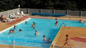 Une piscine dotée de plusieurs couloirs, de chaises longues et d’une zone délimitée par une clôture.