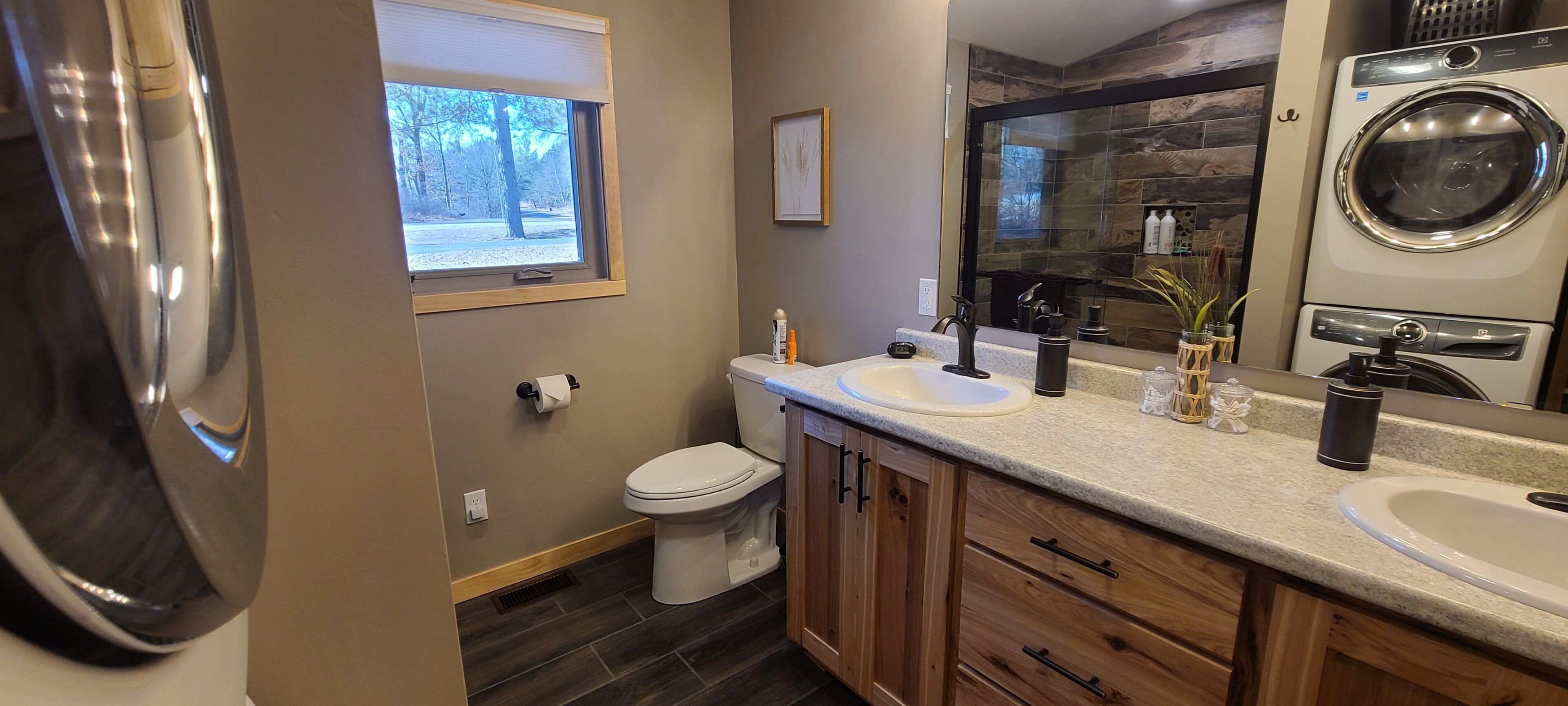 Een moderne badkamer met toilet, twee wastafels, een grote spiegel en een inbouw wasmachine.