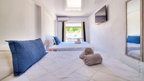 Una camera d'albergo con due letti, una TV fissata al muro e una finestra con tende.