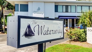 A sign for The Waterway hotel with a modern building in the background.
