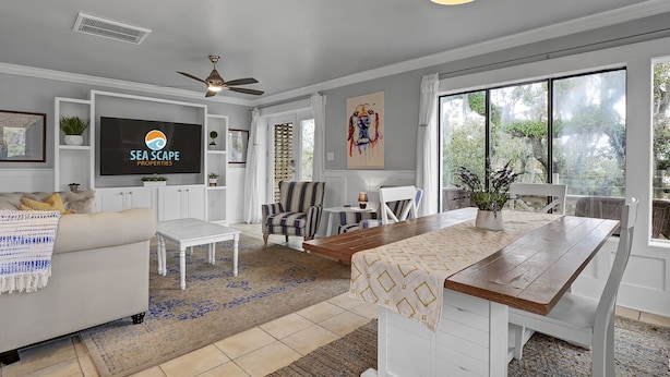 A modern living room with a TV, seating area, and dining space.