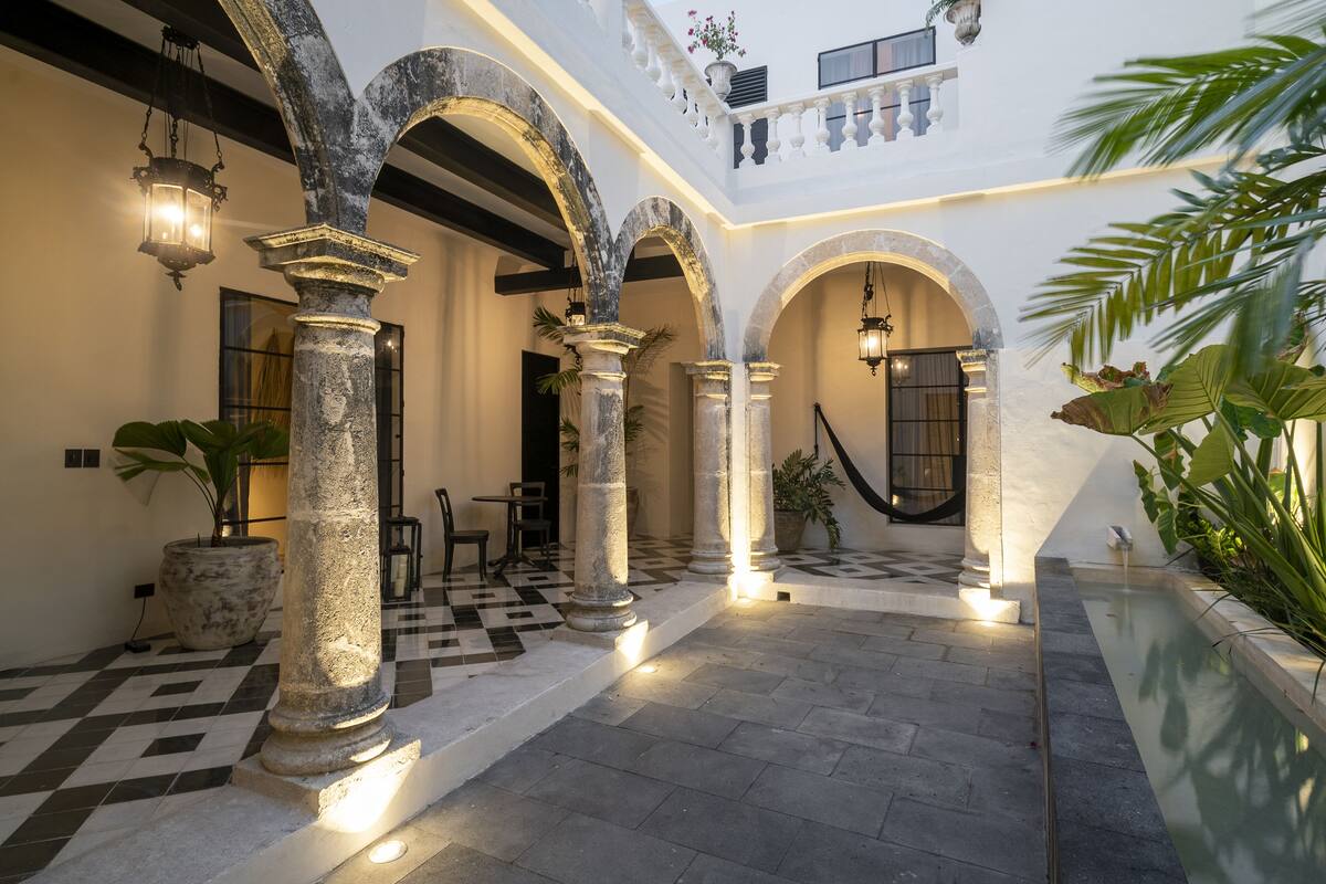A courtyard with stone columns, a checkered floor, and a pool.
