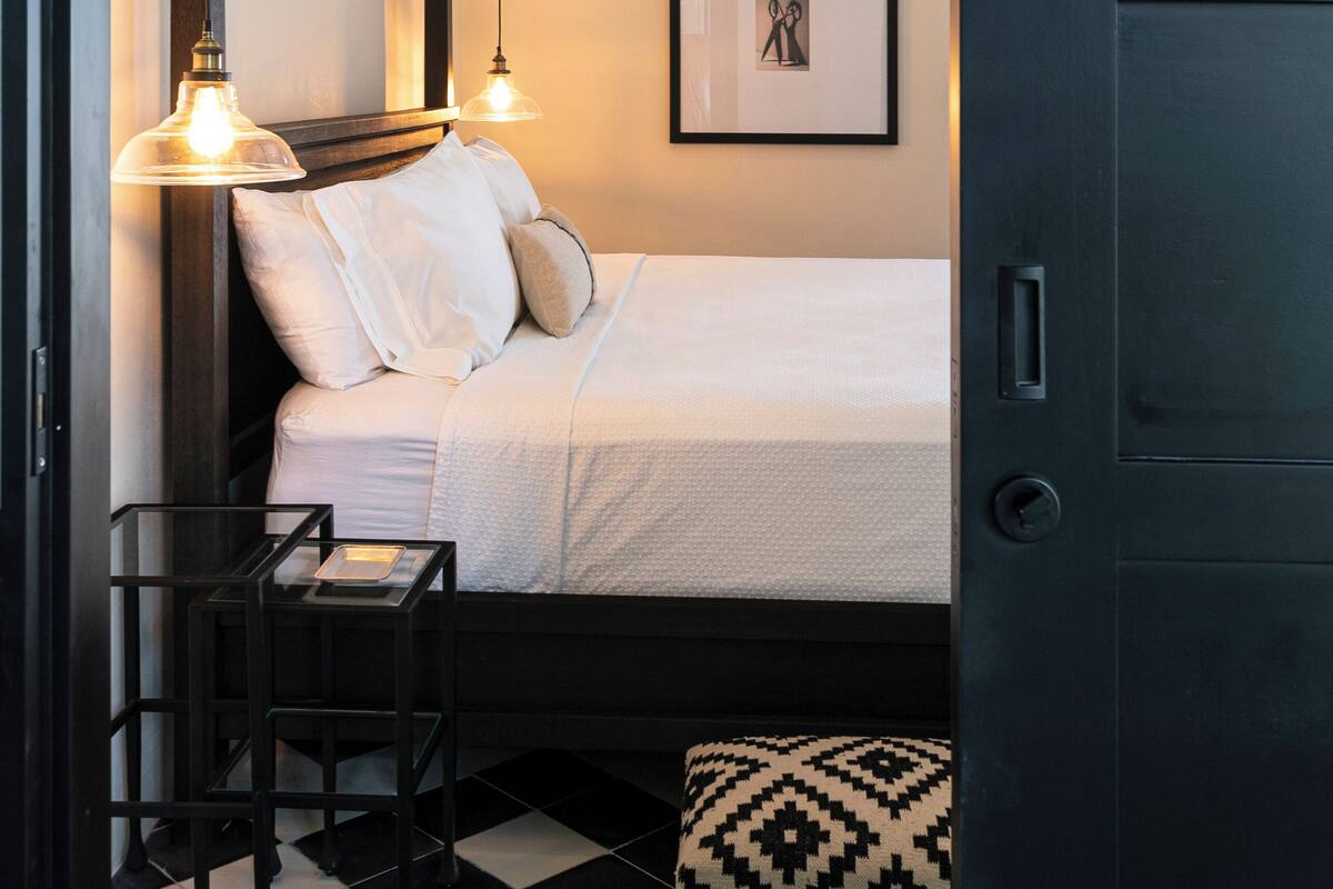 A neatly arranged bedroom with a bed, bedside tables, and a framed picture on the wall.
