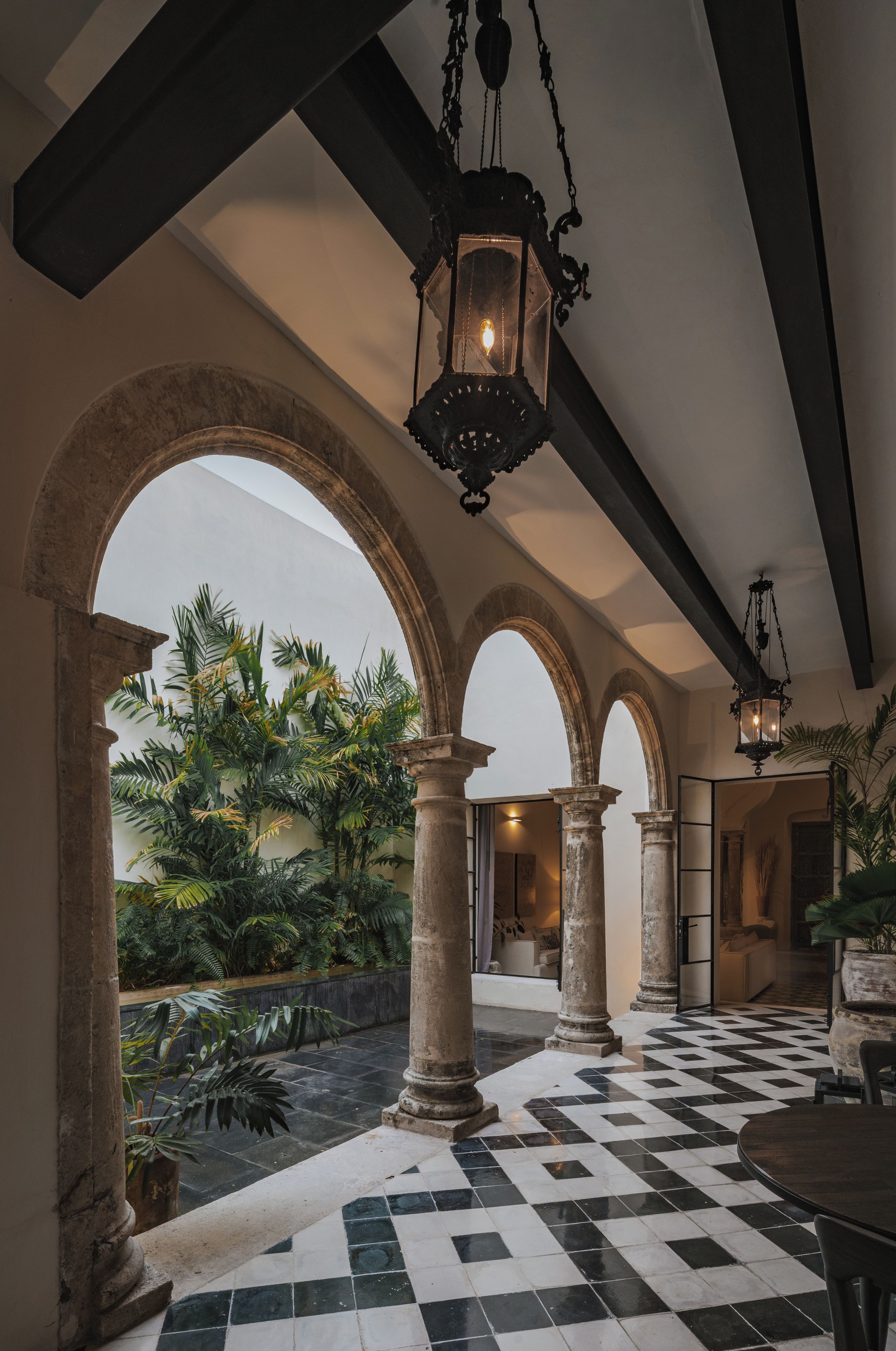 A spacious indoor area with a checkered floor, large stone columns, and hanging lanterns.