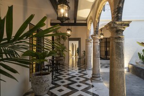 A corridor with a checkered floor, columns, and potted plants. - Casa Japa by Casonas MX (Campeche)