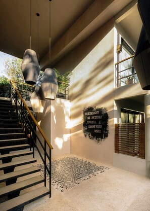 A modern interior with a staircase, pendant lights, a motivational quote on the wall, and a patterned rug. - Attha Bliss Swim Up Studio Beach Club Access (Tulum)