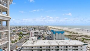 A multi-story hotel with a rooftop pool, overlooking a beach and cityscape. - Oceanfront 3BR Residence with Wraparound Veranda (Wildwood)
