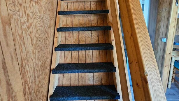 Een houten trap met beklede treden en een houten leuning.