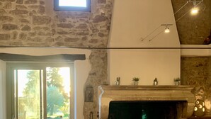 Ein rustikales Interieur mit einer Steinwand, einem Kamin, einem großen Fenster und einer hölzernen Bank.