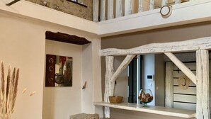Ein rustikales Interieur mit freiliegenden Steinwänden, einem Holzespeisesaal und einem Erker mit weißer Geländer.