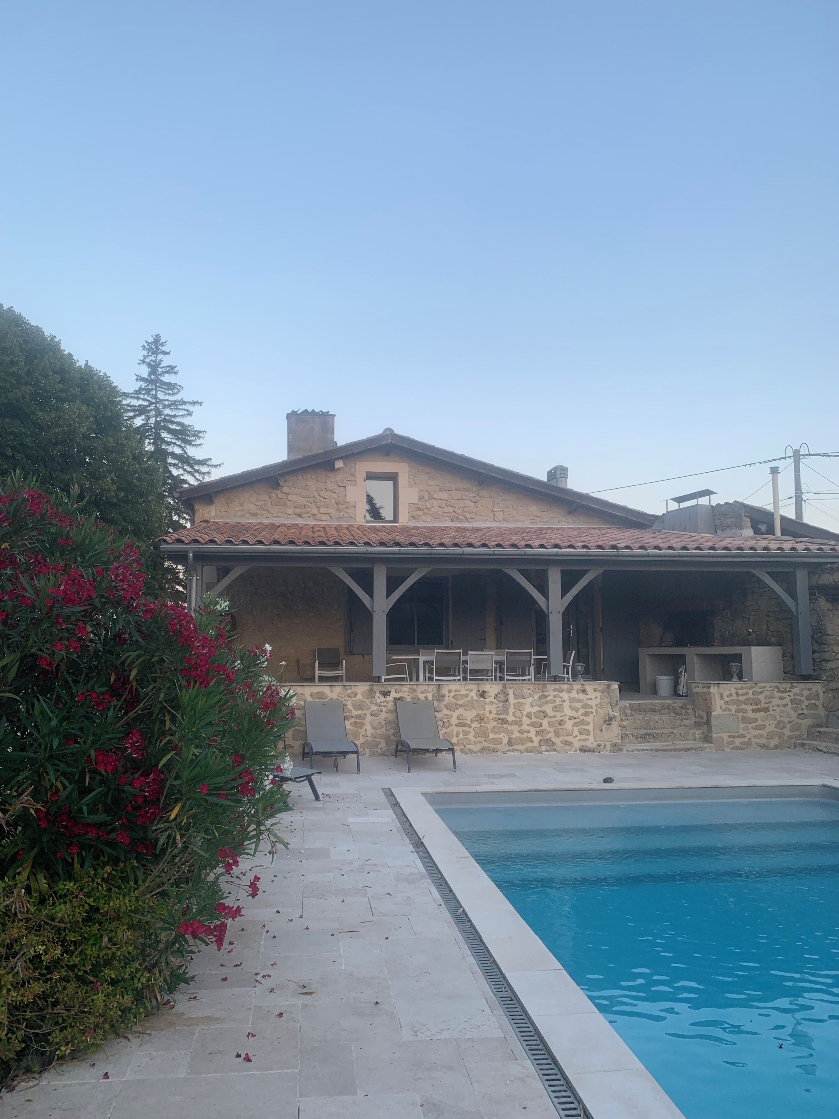 A stone building with a tiled roof, a swimming pool, and outdoor seating.