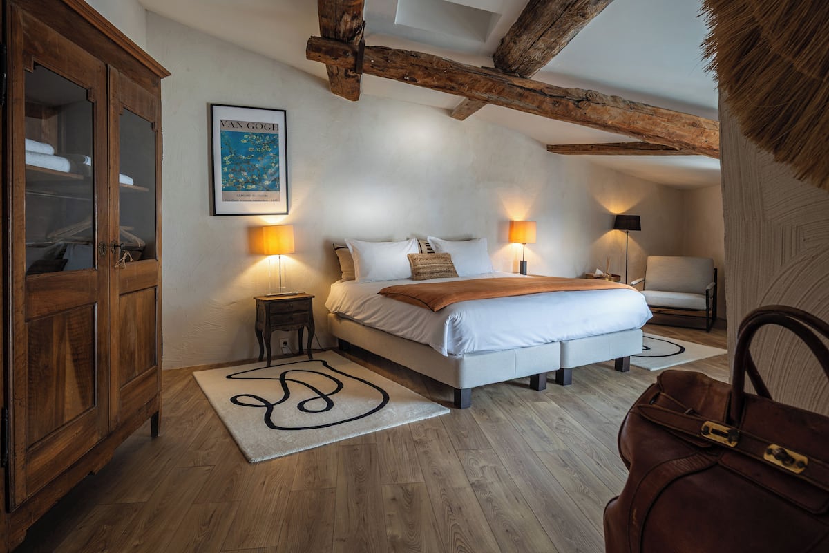 Een slaapkamer met een bed, nachtlampjes, een kledingkast en een lijst aan de muur.