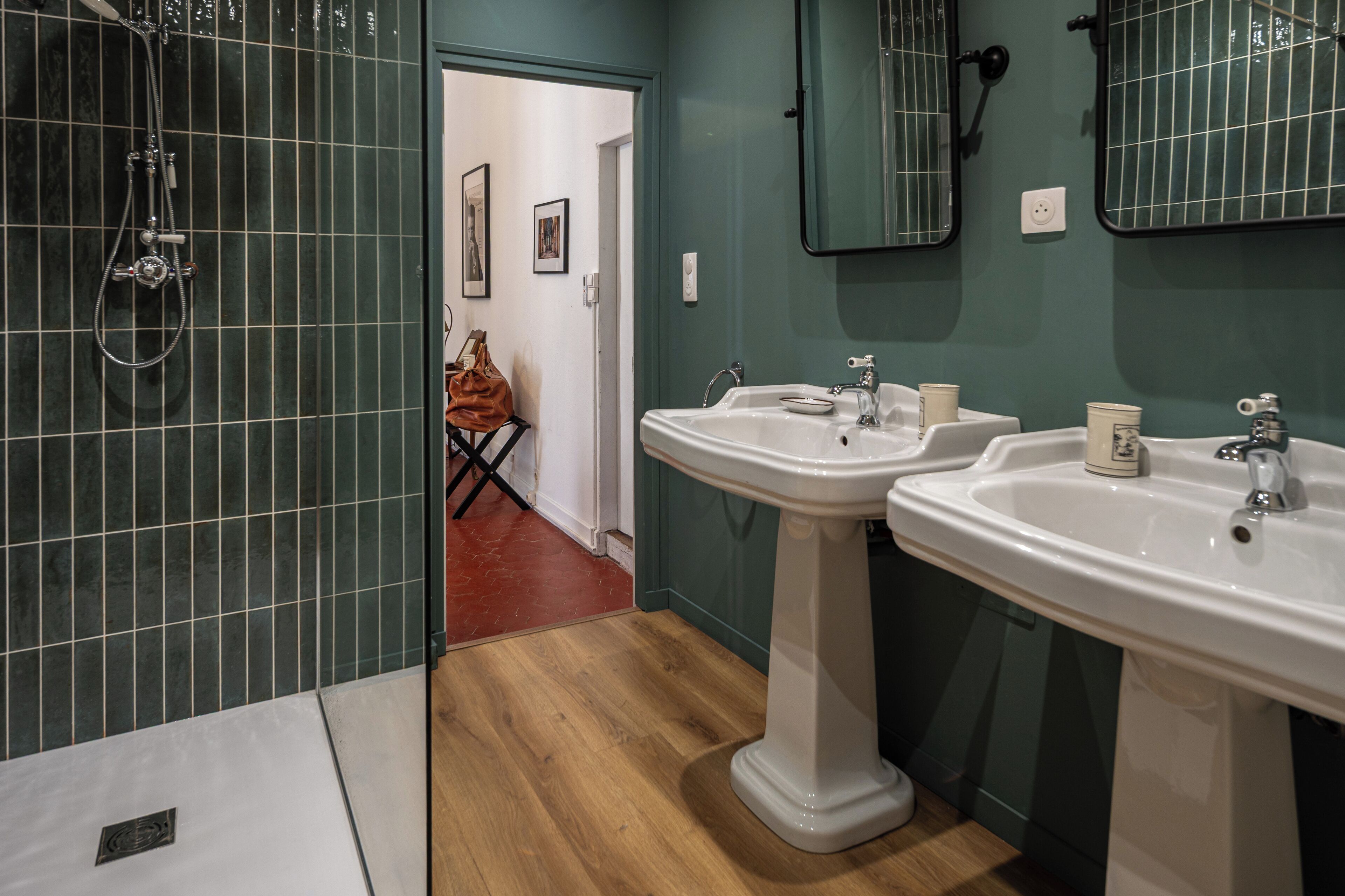 Un baño con dos lavamanos, ducha y espejo.