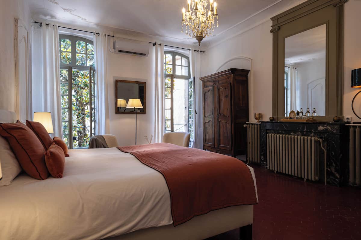 Een slaapkamer met een groot bed, een kroonluchter, een spiegel en een radiator.