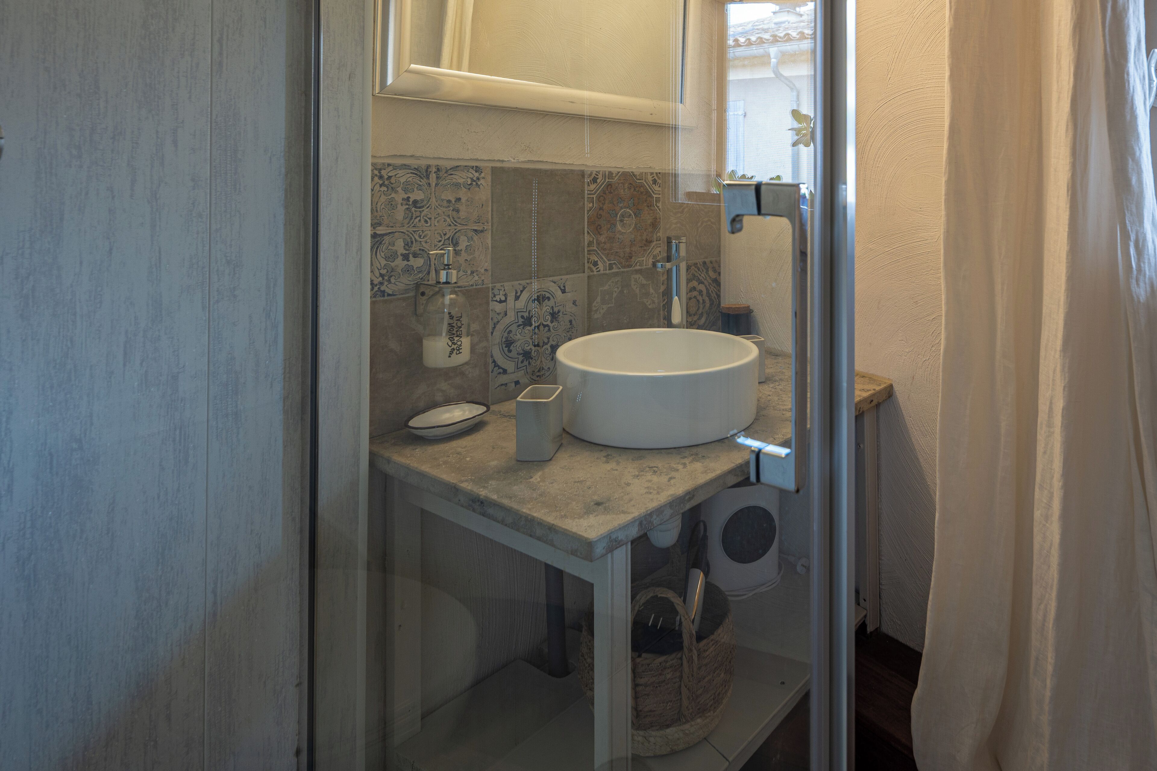 Een badkamer met een rond wastafel, toilet en douche.